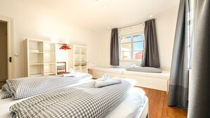 Ein Hotelzimmer mit zwei Betten, einem Kleiderschrank, einem Fenster mit Vorhängen und Blick nach draußen.
