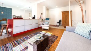 Ein modernes Wohnzimmer mit einer Couch, einem Couchtisch, einem Holzschrank und einem farbenfrohen Teppich.