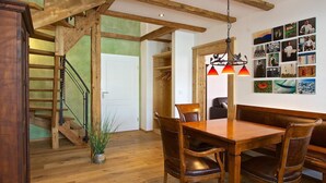 Una escalera de madera que conduce a un dormitorio en el altillo con techo inclinado.