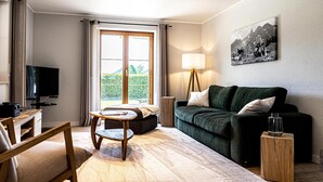 Ein modernes Wohnzimmer mit einer Couch, einem Couchtisch, einem Fernseher und einer Lampe.