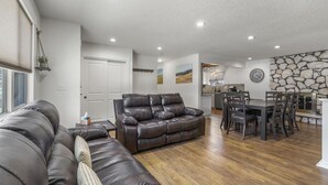 A spacious living room with a leather sofa, wooden dining table, and chairs.
