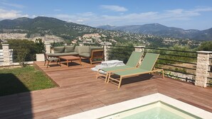 Eine Dachterrasse mit Pool, Sitzgelegenheit und Blick auf eine gebirgige Landschaft.