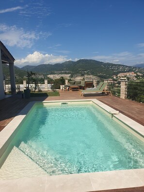 A swimming pool with a view of mountains and a town in the background.