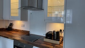 Una cucina moderna con piano cottura integrato, cappa aspirante e macchina per il caffè sul piano di lavoro.