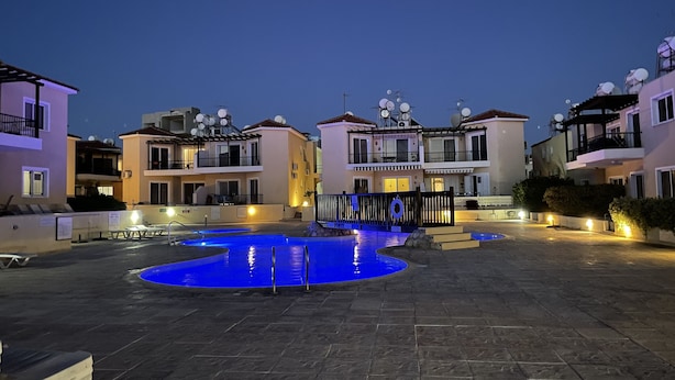 Zona residencial con piscina, varios edificios de apartamentos y antenas parabólicas en los tejados.