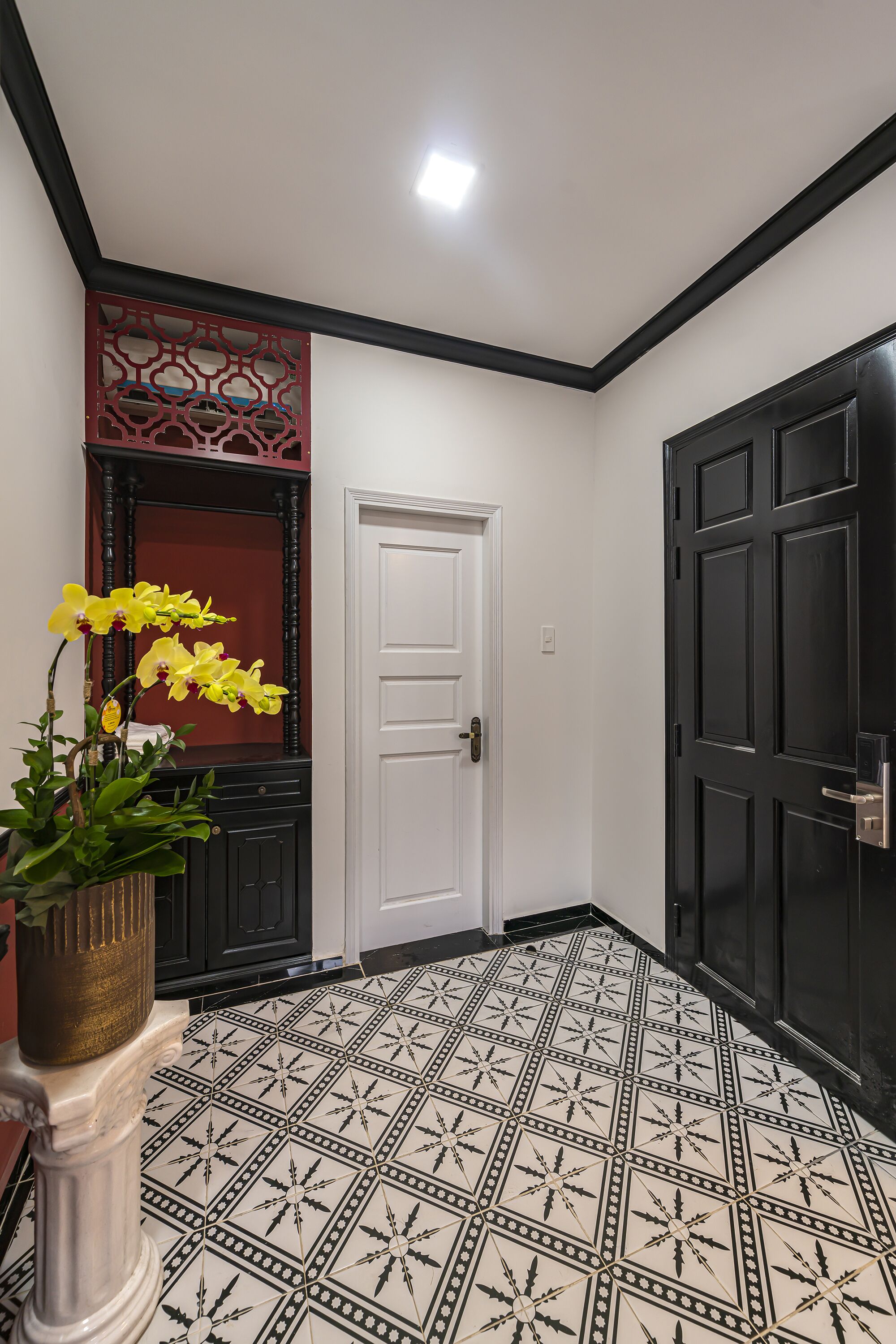 A hallway with a white door, black doors, and a patterned floor.