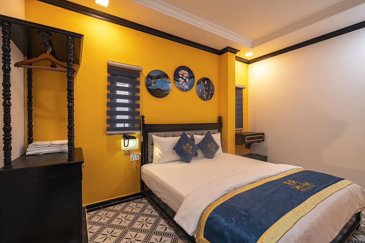 Une chambre d’hôtel comprenant un lit, une commode, un miroir et trois éléments de décoration murale.
