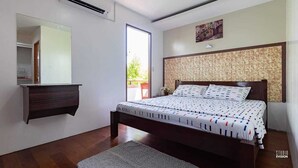 Quarto com cama, penteadeira, espelho e janela.
