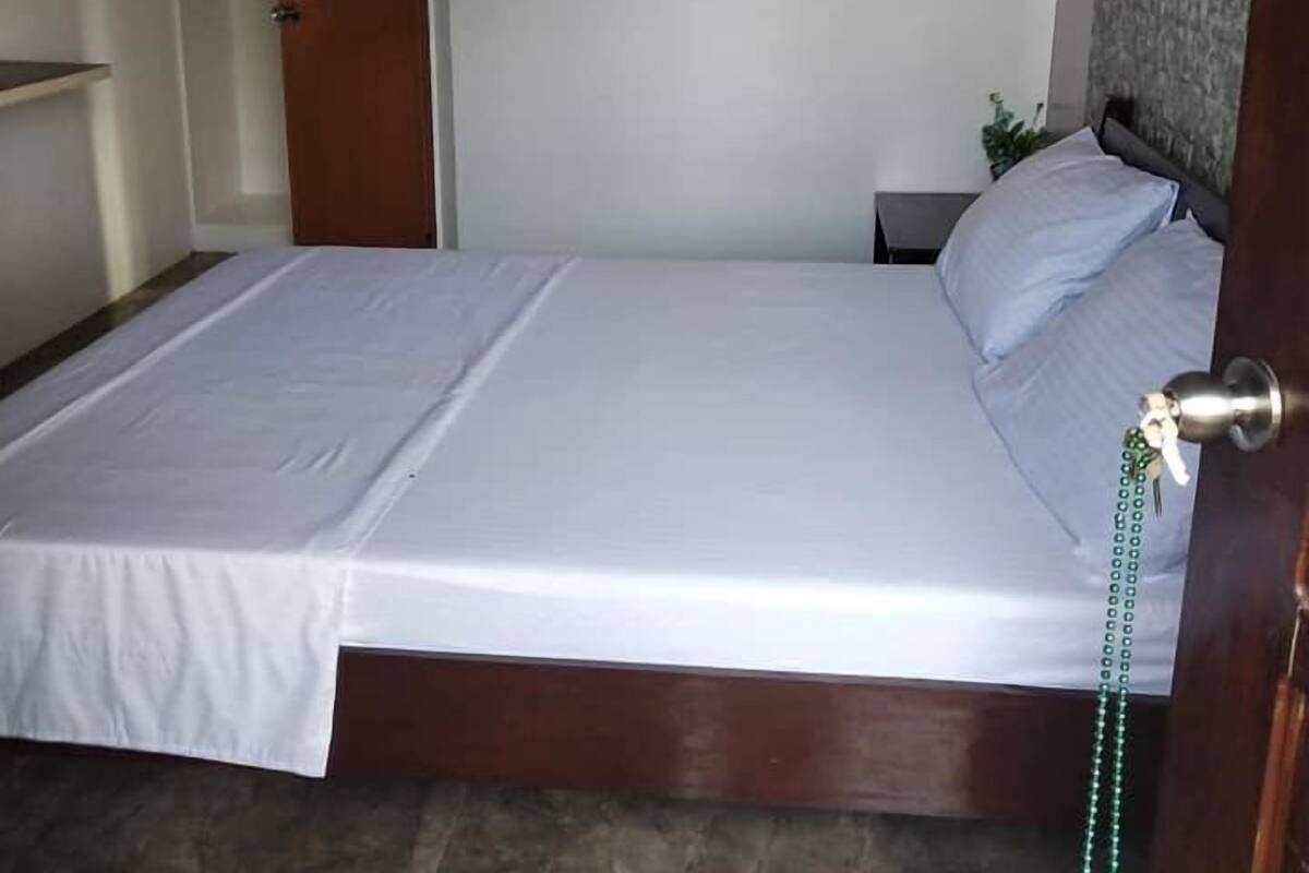 A bedroom with a bed, a nightstand, a painting on the wall, and a door.