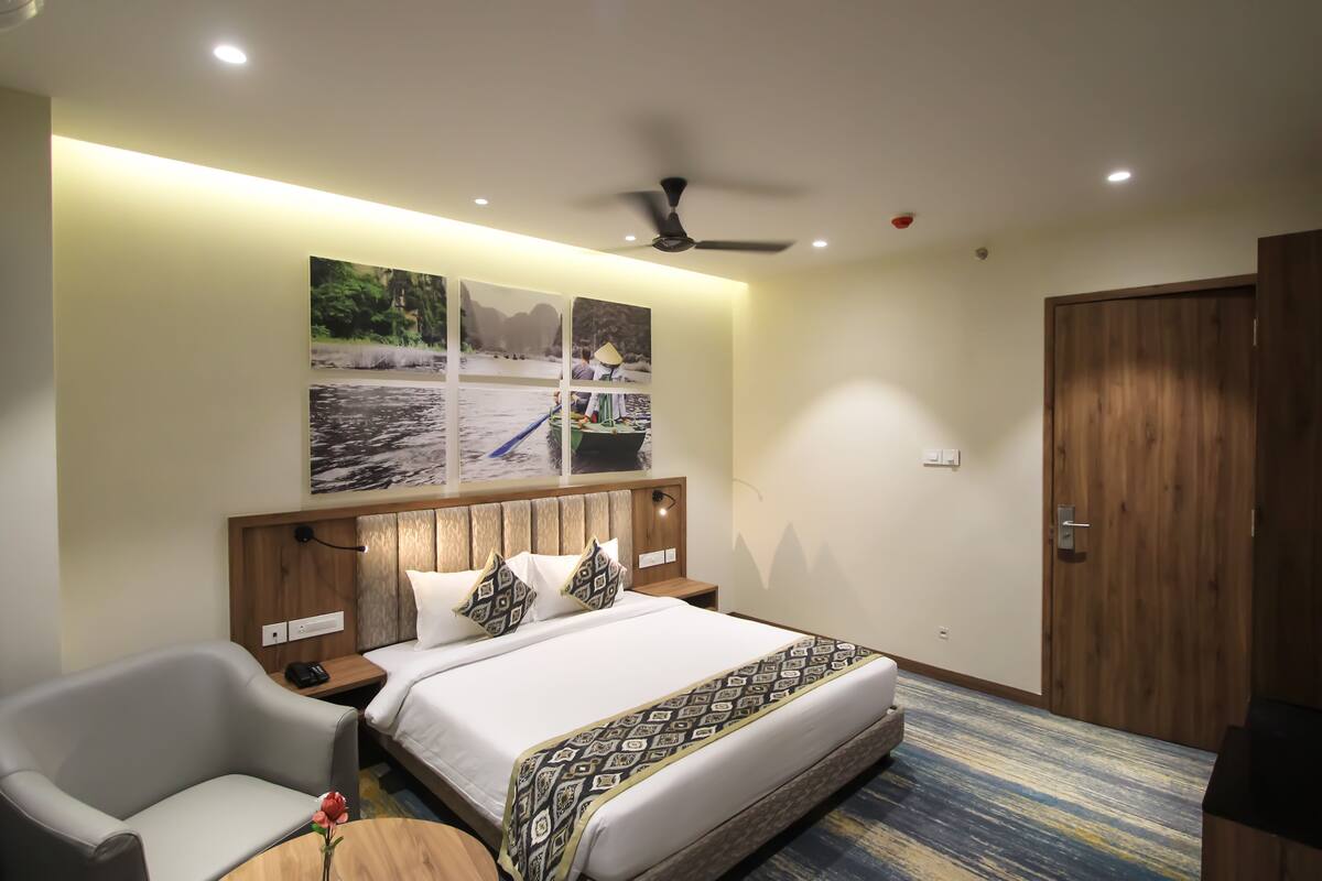 A hotel room with a bed, a chair, a desk, and a ceiling fan.