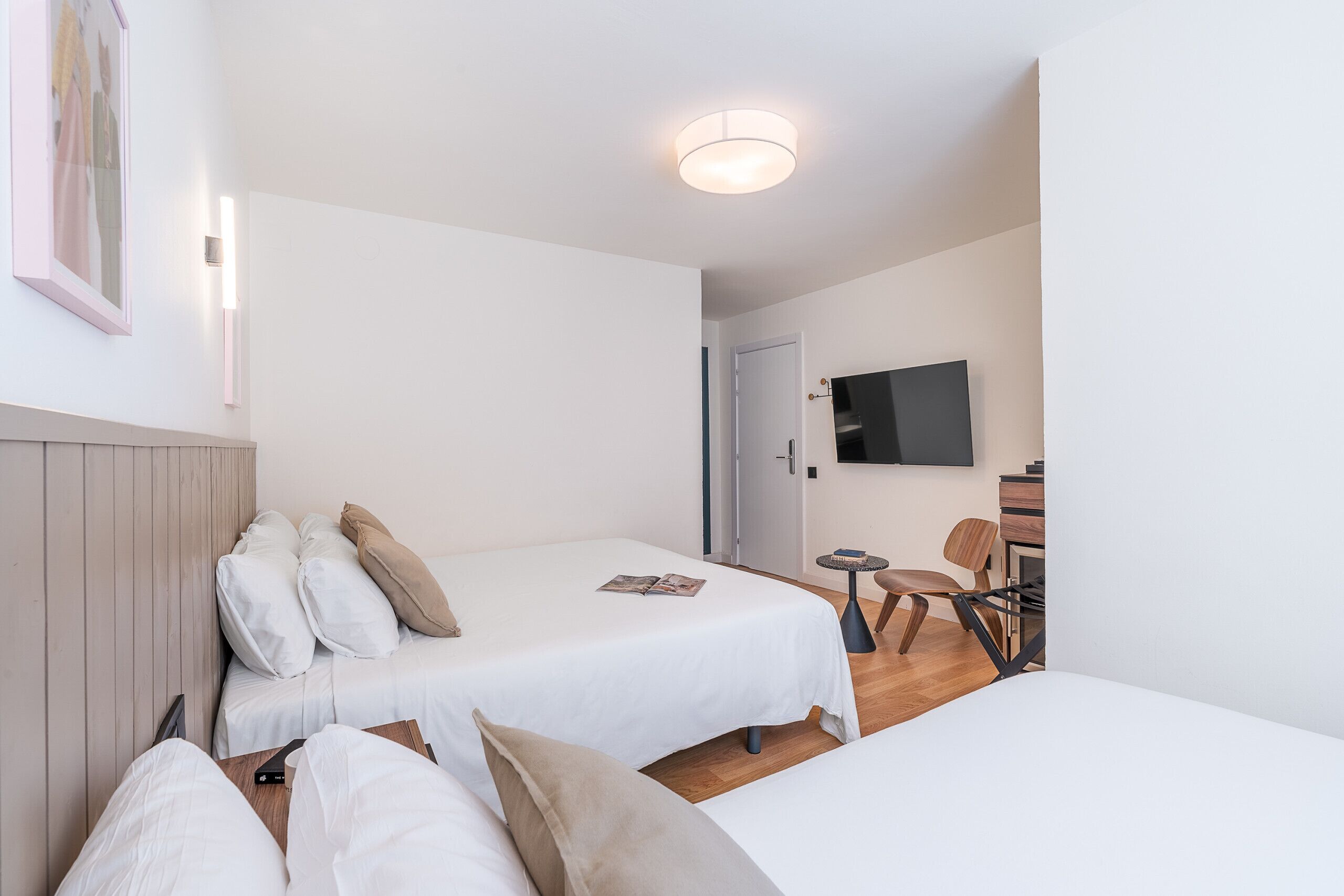 A hotel room with two beds, a television, a small table, and a chair.