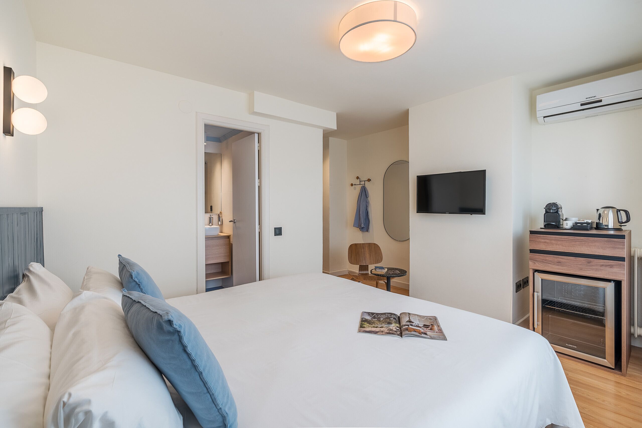 Una habitación de hotel con cama, televisión, una mesita y una kitchenette.