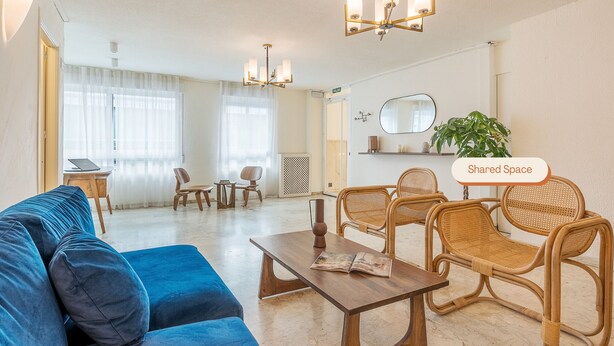A modern living room with a blue sofa, wooden chairs, a coffee table, and a chandelier. - Granada Suites by Olala Homes (Granada)