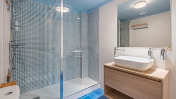 Driepersoonskamer | Badkamer | Een douche, een haardroger, handdoeken, zeep