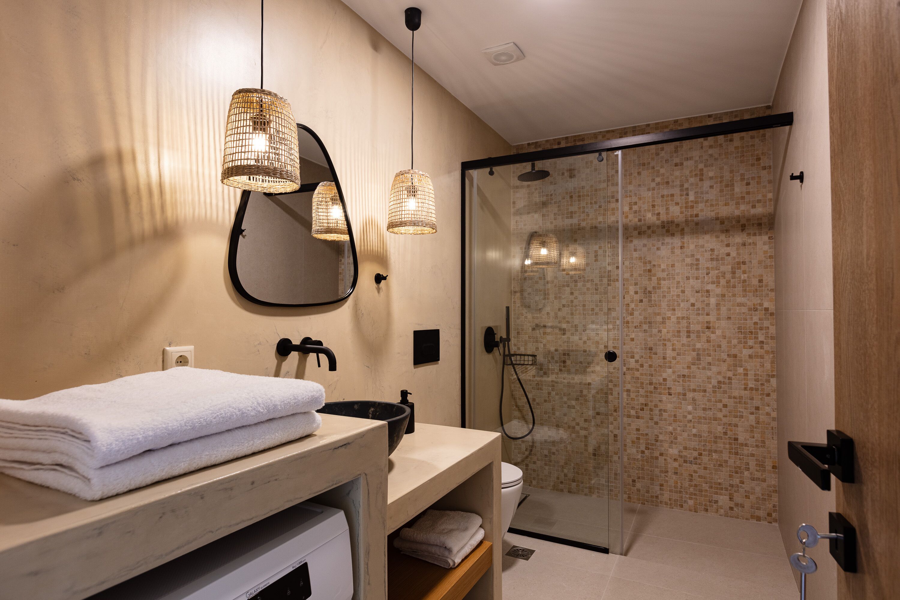 Ein modernes Badezimmer mit Waschbecken, Spiegel, Handtuchhalter und einer Duschkabine.