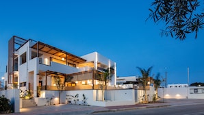 Une maison moderne à deux étages, dotée d’un balcon, d’un patio couvert et d’un éclairage extérieur soigné.