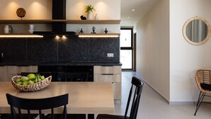 Une cuisine moderne dotée d’un plan de travail en granit foncé, de meubles en bois et d’un coin repas avec une table et des chaises.