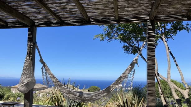 Un hamac sous une pergola en bois, avec vue sur l’océan.