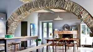 Un espace repas agrémenté d’une arche en pierre, de tables et de chaises en bois.