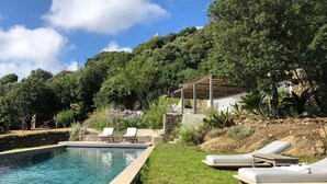 Une piscine avec des chaises longues et une pergola.