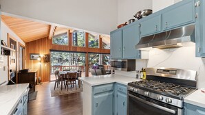 Una cocina moderna con armarios azules, una estufa a gas y un amplio ventanal con vistas a una terraza.