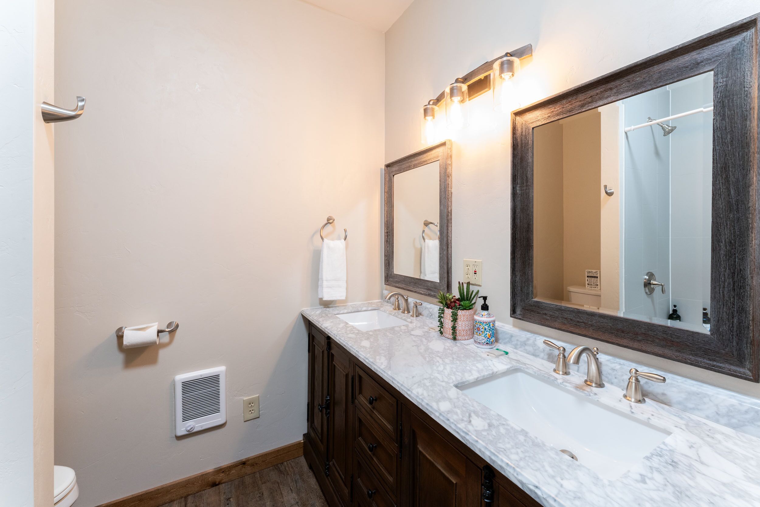 A bathroom with two sinks, a large mirror, and a shower.