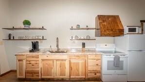 A kitchen with wooden cabinets, a granite countertop, a sink, a stove, and a microwave. - North Fork of Spotted Bear Retreat (Columbia Falls)