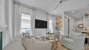 A modern living room with a white sofa, a coffee table, and a TV. - Amazing Location, Golf Cart, Gorgeous New Construction! (Santa Rosa Beach)