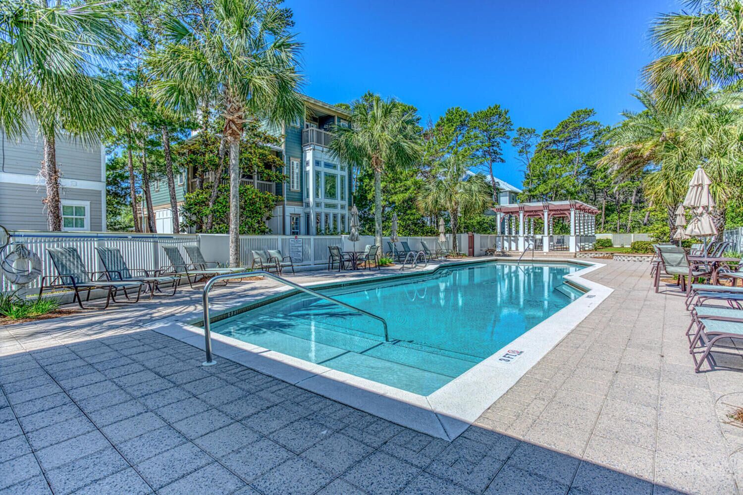 A swimming pool with lounge chairs and palm trees.