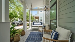 A covered porch with a blue patterned rug, wicker furniture, and a white sofa with blue cushions. - Amazing Location, Golf Cart, Gorgeous New Construction! (Santa Rosa Beach)