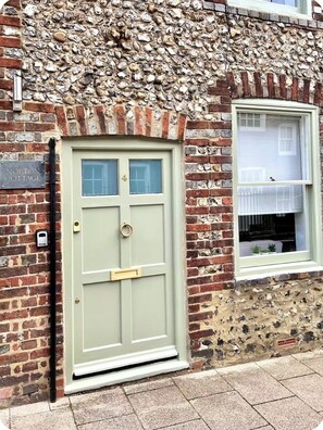 A traditional brick building with a stone facade, a green door, and a window with a white frame. - Cottage in Arundel, West Sussex
 (Arundel)