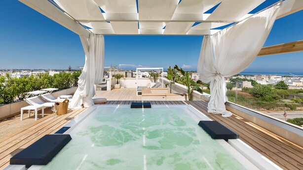 Piscina infinita en la azotea con vistas despejadas a la ciudad y al mar.