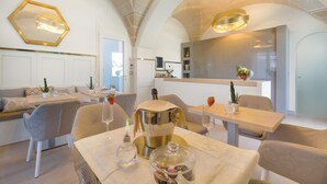 Un comedor moderno con una estación central para postres dorada, paredes blancas y techos abovedados.