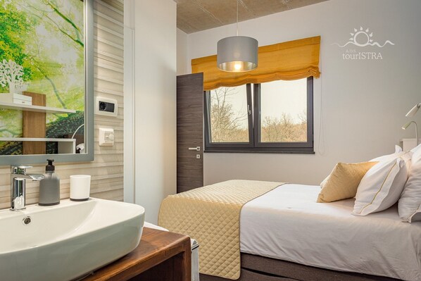 A bedroom with a bed, bedside table, and a window with a view.