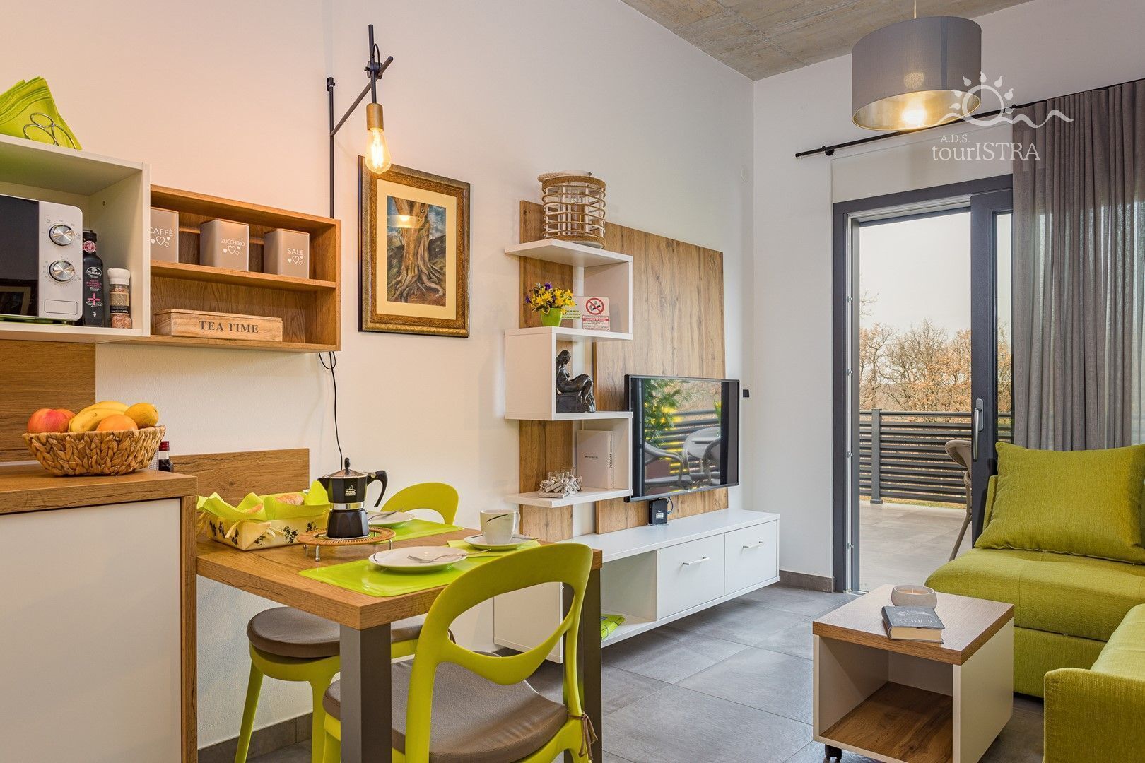 A modern living room with a dining area, a coffee machine, and a flat-screen TV.