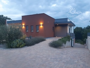 A modern building with a brick facade, a paved driveway, and a well-maintained garden area.