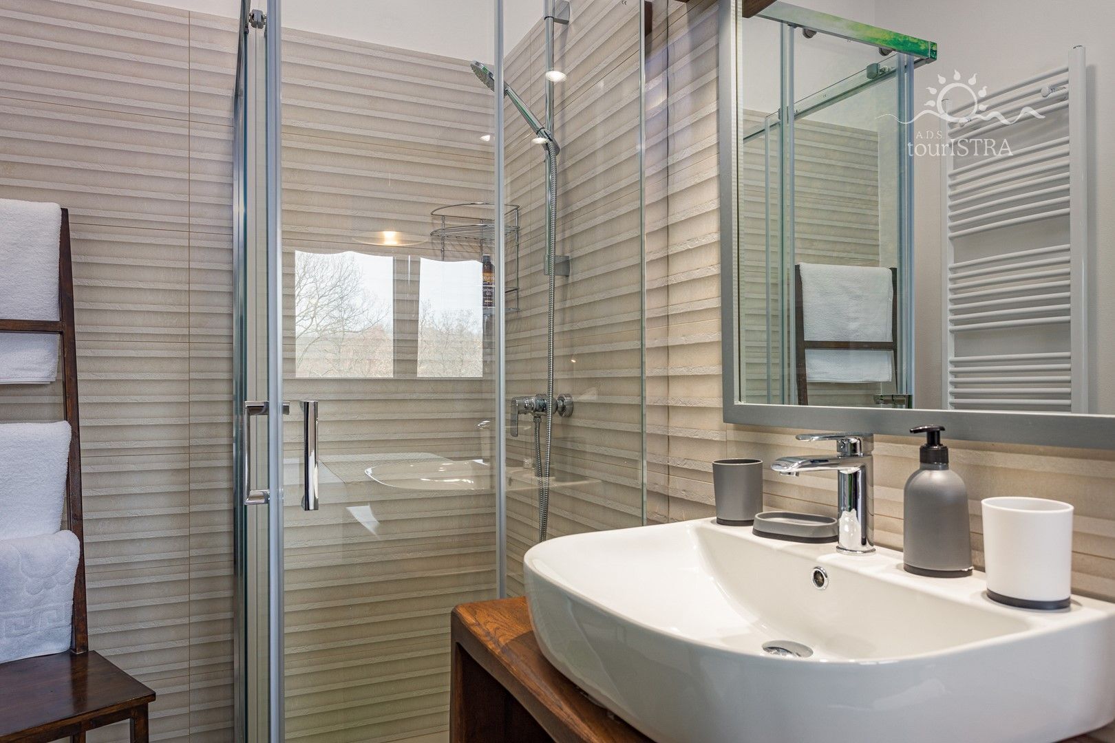 A modern bathroom with a glass shower enclosure, a large sink, and a mirror.