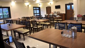 A restaurant with multiple tables and chairs, a kitchen area, and a washroom. - The Byke Skylark Seafront Resort, Dapoli (Dapoli)