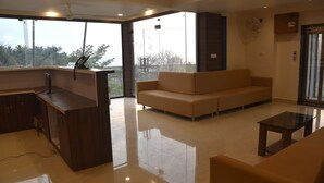 A modern living room with a sofa, a glass coffee table, and a kitchen area with a countertop and cabinets. - The Byke Skylark Seafront Resort, Dapoli (Dapoli)