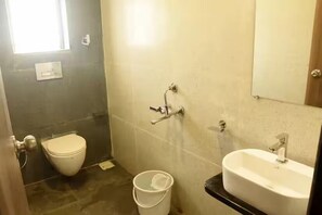 A bathroom with a toilet, a sink, and a bucket.