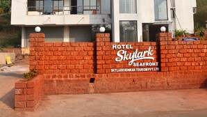A multi-story hotel with balconies, a brick wall in front, and a clear sky. - The Byke Skylark Seafront Resort, Dapoli (Dapoli)