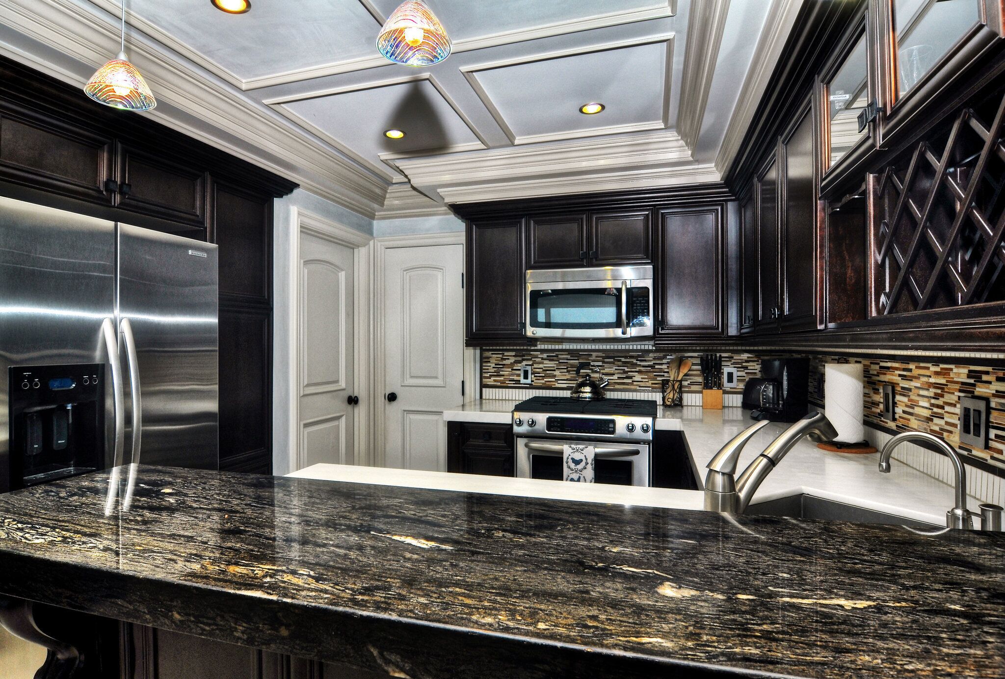 A modern kitchen with dark cabinetry, stainless steel appliances, and a granite countertop.