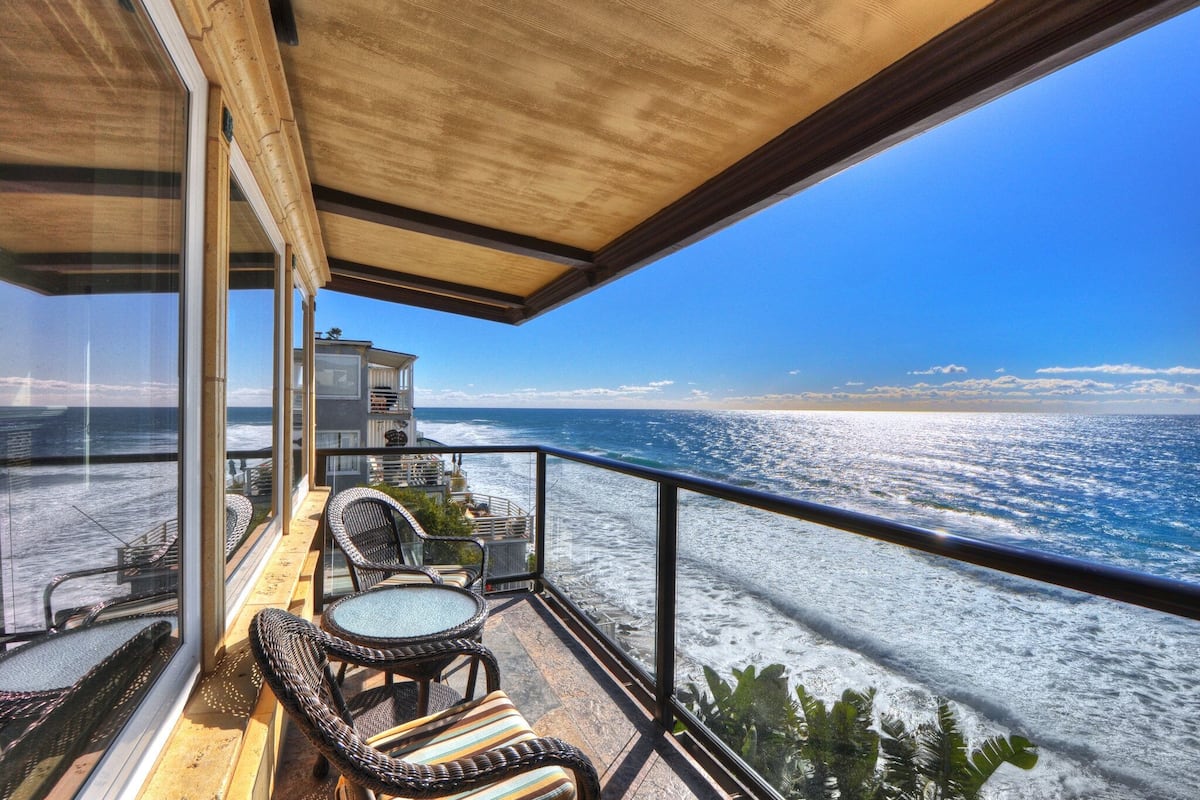 A balcony with wicker furniture and a view of the ocean.