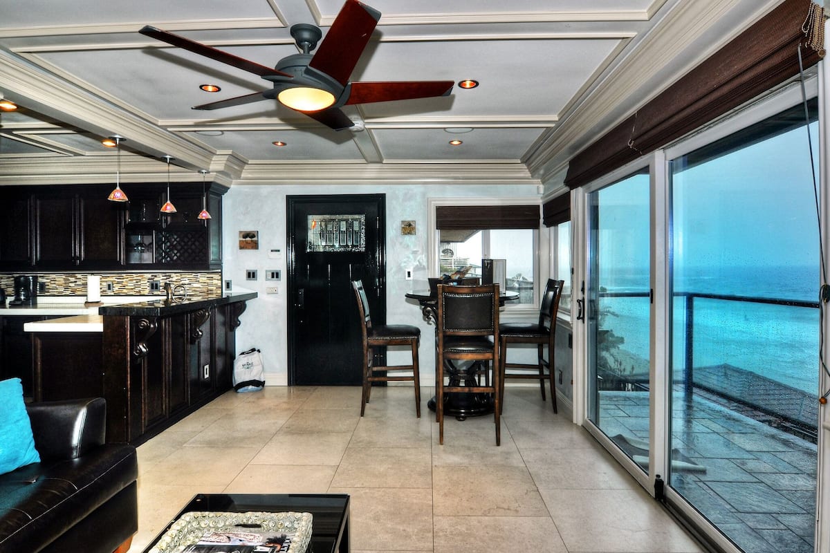 A spacious living area with a large sliding glass door leading to a balcony with a view of the ocean.