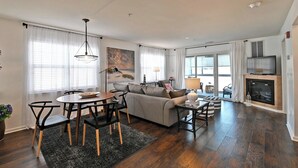 Un salon moderne comprenant un canapé, une table à manger et des chaises, une cheminée et un téléviseur.