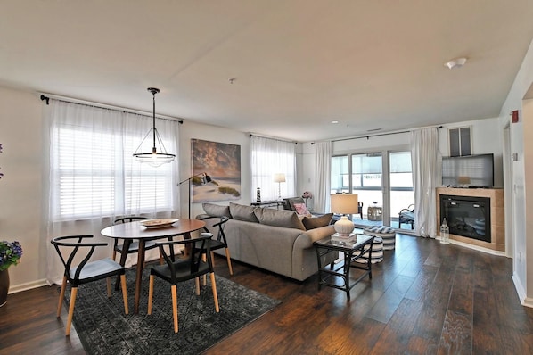 A modern living room with a sofa, dining table, and chairs, a fireplace, and a TV.