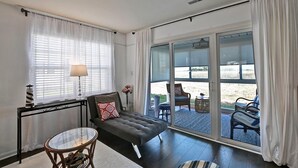 Un salon moderne avec un canapé, une table basse en verre et une vue sur l’extérieur grâce à de grandes portes-fenêtres coulissantes.