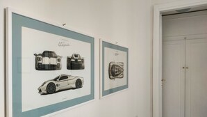 Zwei gerahmte Auto-Illustrationen an einer Wand.