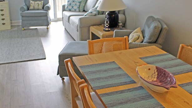 Una sala de estar con una mesa de comedor de madera, sillas, un sofá y una lámpara.