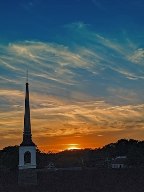 Um monumento alto com topo pontiagudo, emoldurado por um céu de pôr do sol com nuvens.